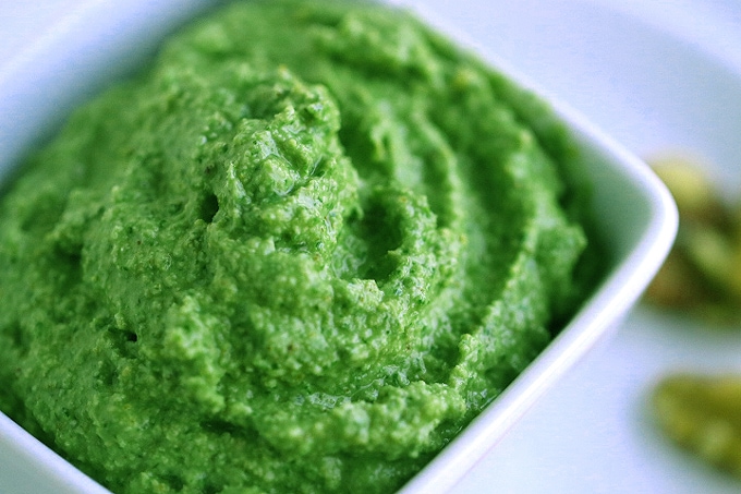 A close up of a bowl of pesto sauce in a white bowl