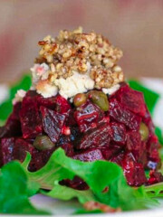 beet tartare on white plate surrounded by greens