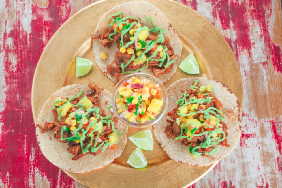 three tacos on a gold plate with mango corn salsa 