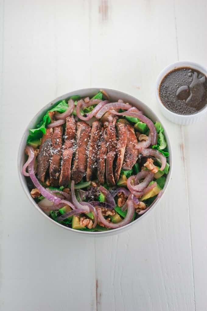 A mushroom salad in a white bowl on a white table