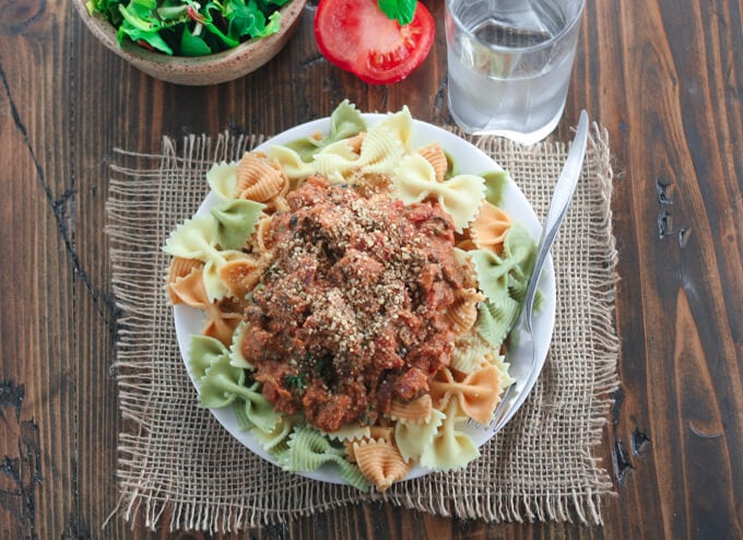 A plate of pasta with sauce sitting on top of a wooden table