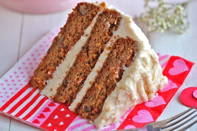 A slice of vegan carrot cake sitting on top of a paper plate