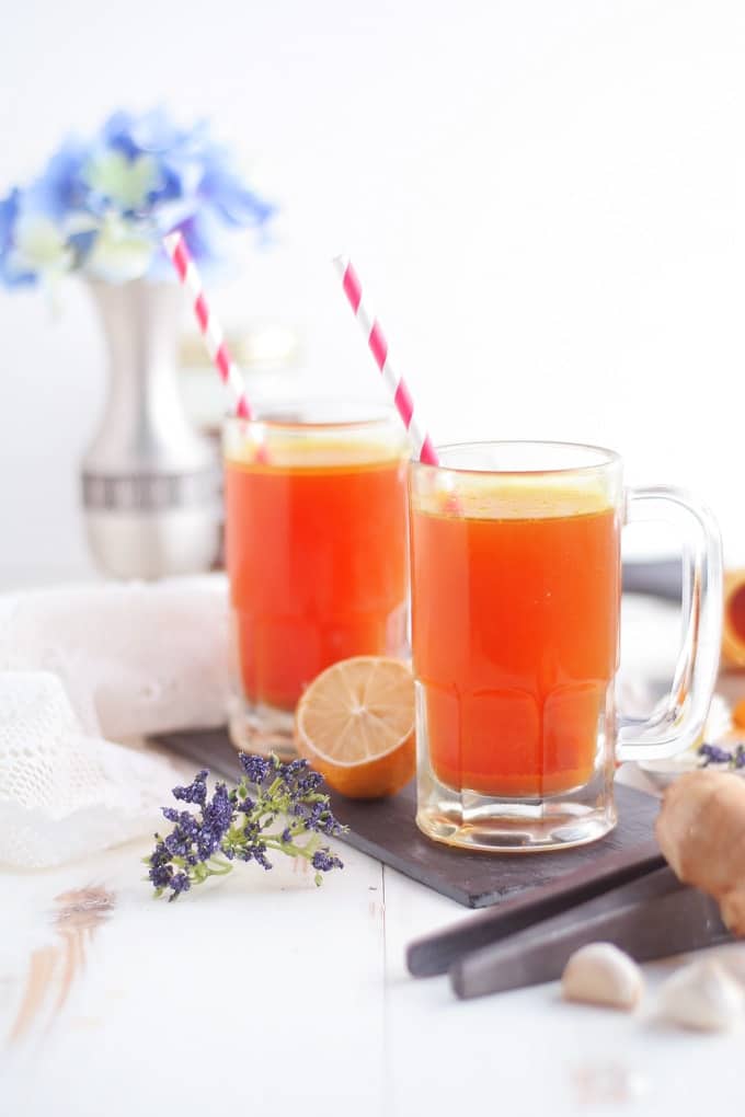 two glasses of turmeric tonic on a white wooden table