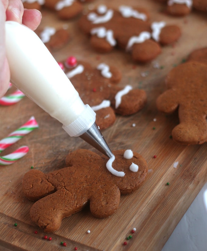 a person decorating a gingerbread man with icing on a cutting board