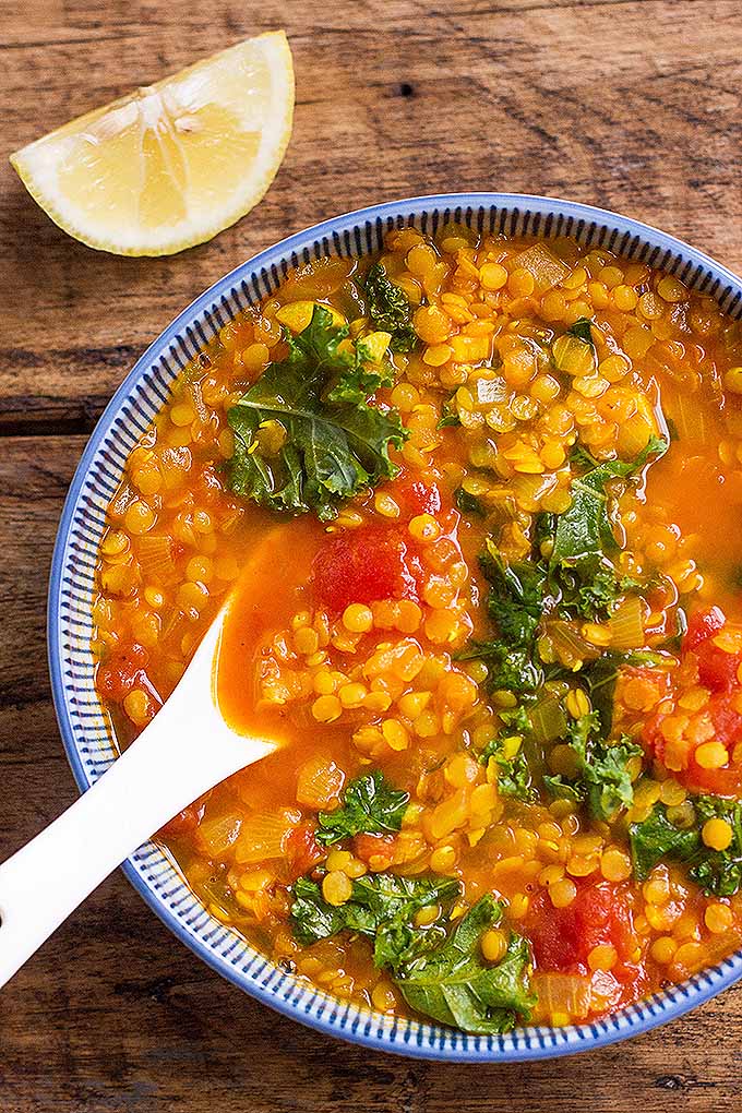 A bowl of red lentil stew sitting on a wooden table