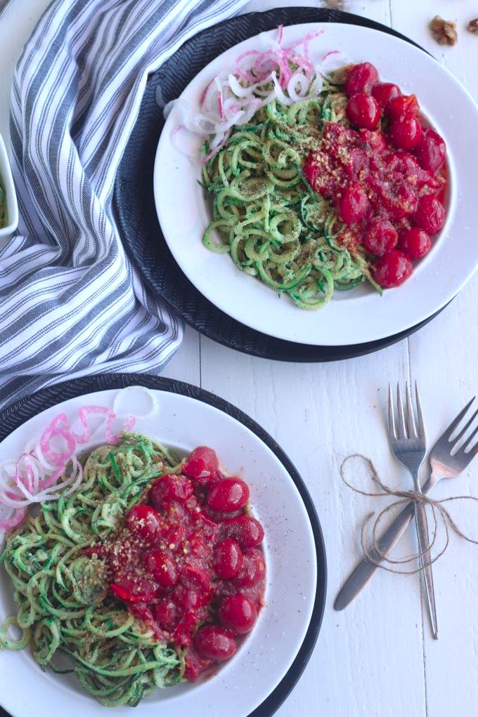 A closeup overhead shot of two plates of pesto zoodles