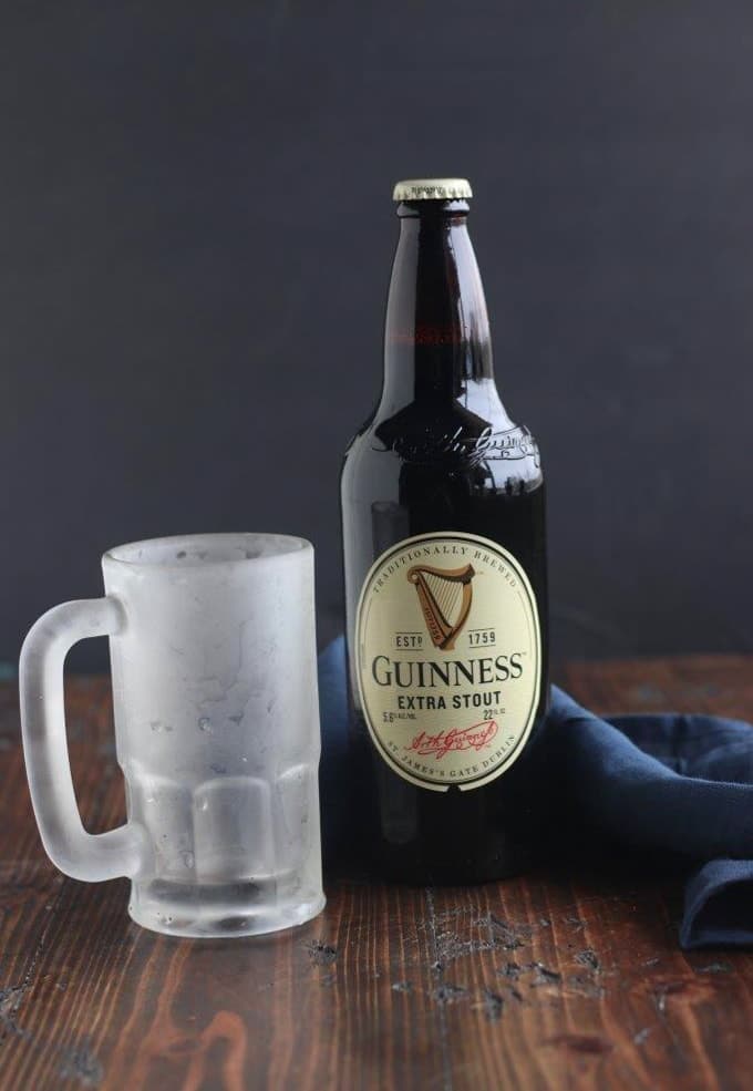 A glass bottle of Guinness next to an icy mug pint