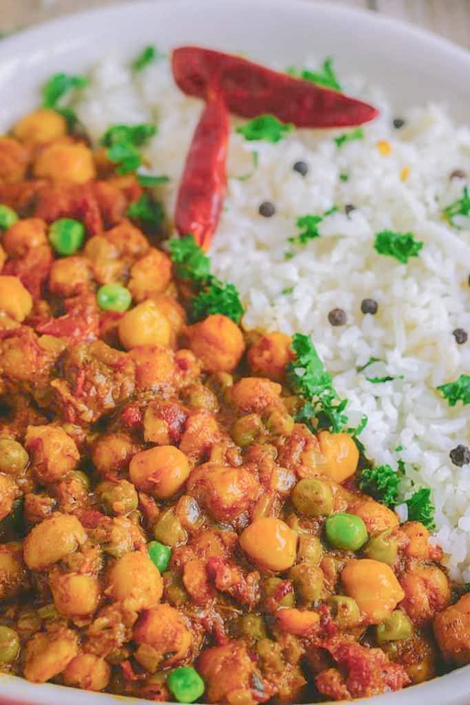 A closeup of curry in a white bowl with white rice next to it