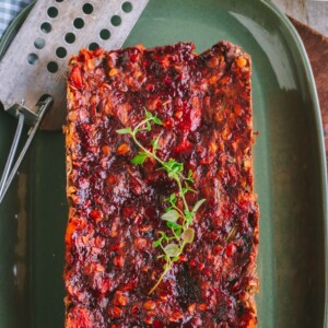 overhead shot of Vegan Lentil Loaf on a green platter topped with red sauce and rosemary