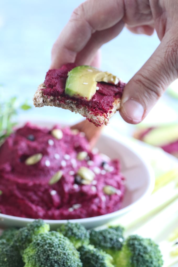 Picture of Hand Offering Camera Bite of Roasted Beet Hummus Recipe with Avocado