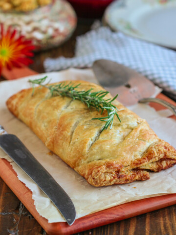 vegan mushroom wellington on a brown table topped with a sprig of rosemary