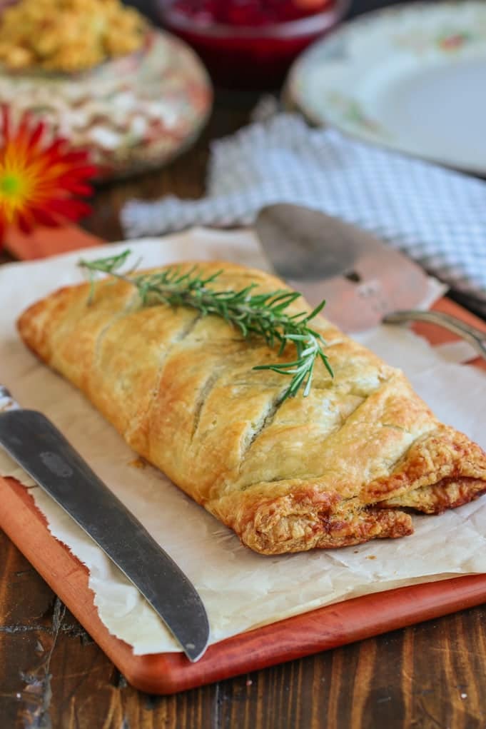 vegan mushroom wellington on a brown table topped with a sprig of rosemary