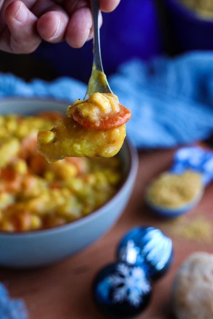 A close up of a person holding a piece of food, with Corn chowder and Soup