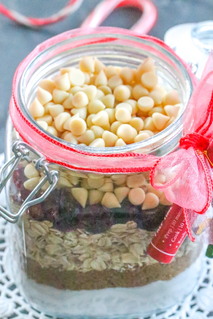 A closeup of white chocolate chips in a jar with other ingredients to make cookies