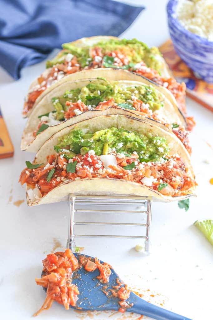 3 Jackfruit Tinga Tacos with toppings on a taco stand