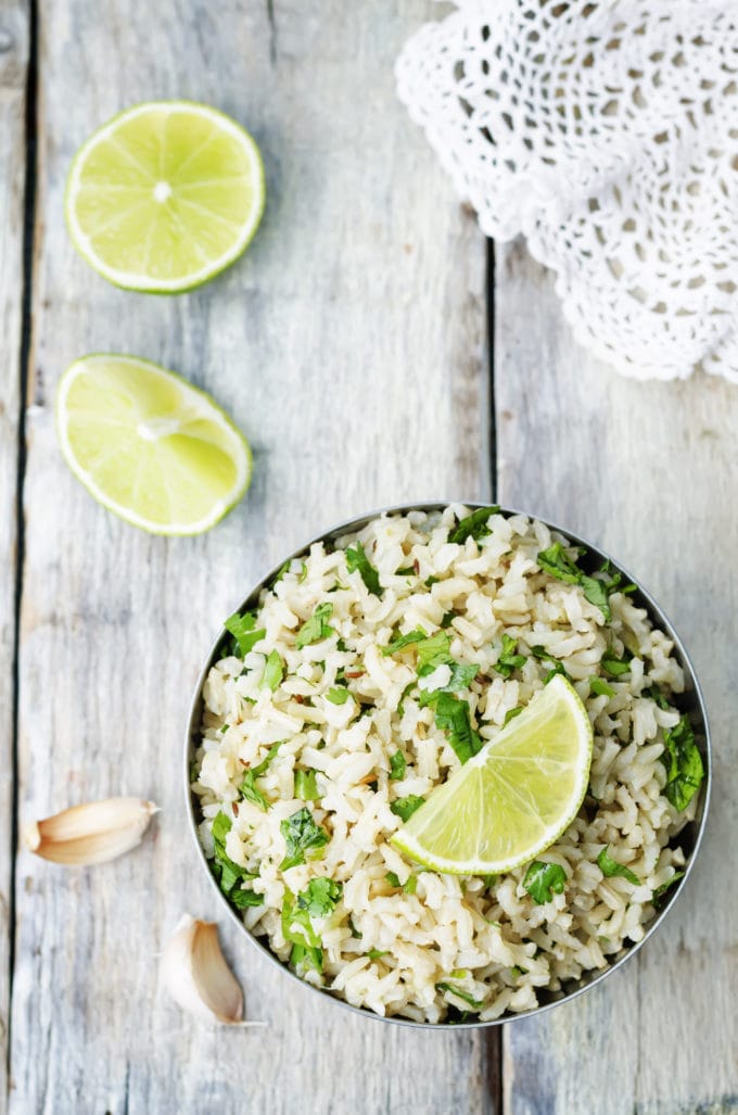 overhead shot of brown rice topped and surrounded by garlic, lime and cilantro