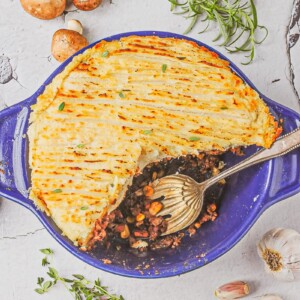 overhead view of Shepherd's pie with slice removed in a blue casserole dish on a white table