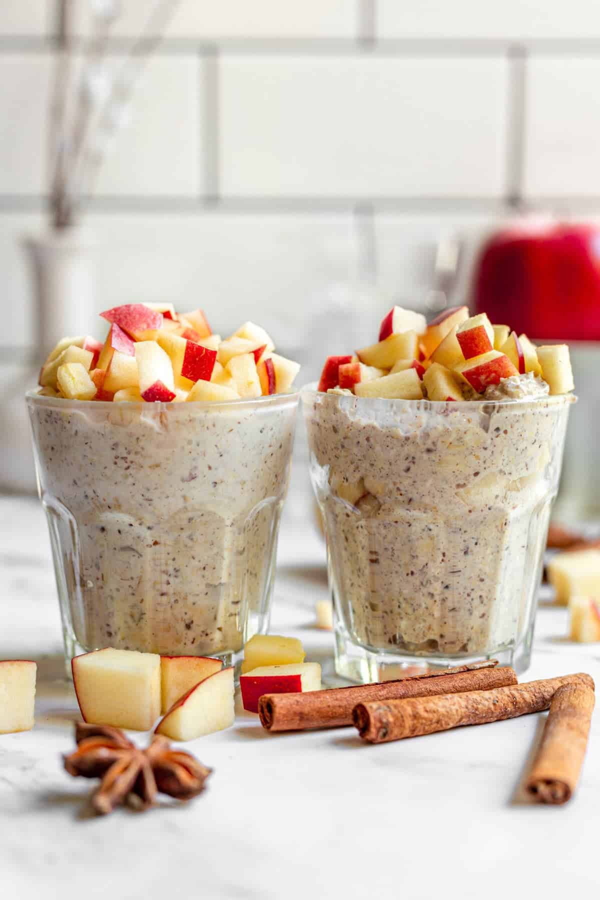 2 glasses over oats with apples side by side on a white table