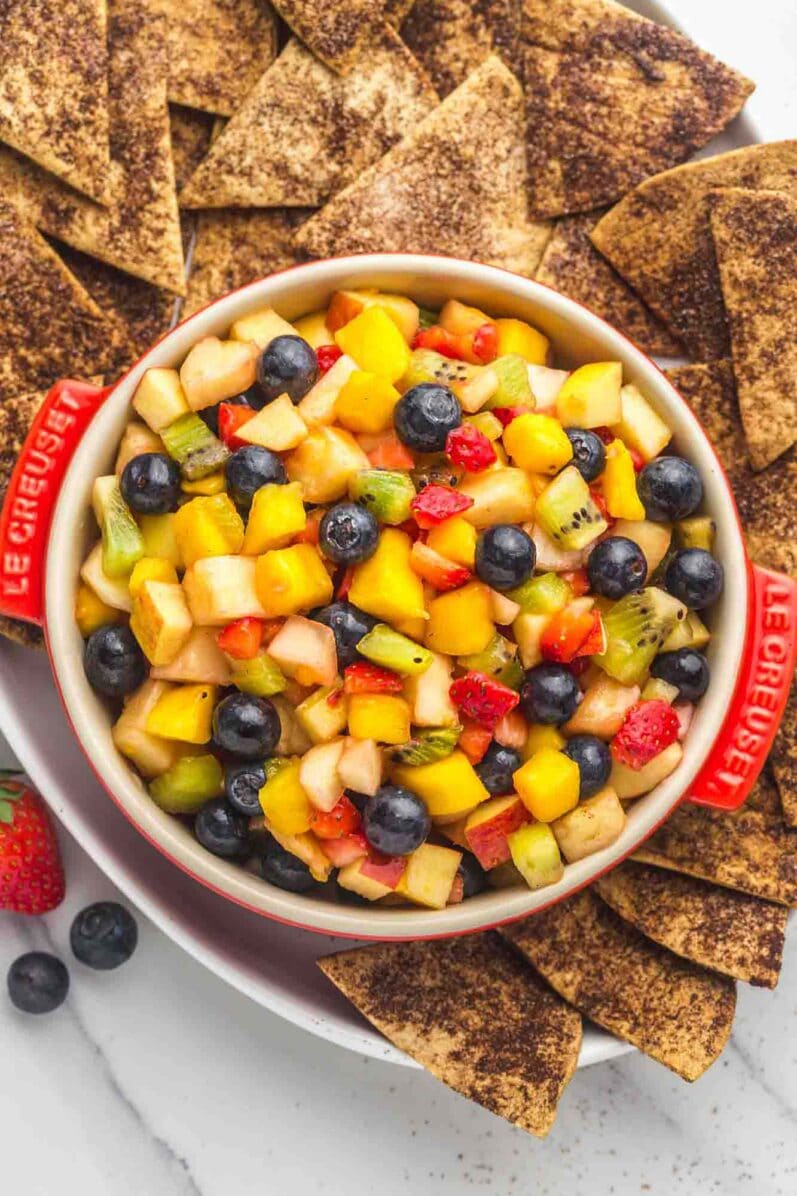 fruit salsa in a white bowl surrounded by cinnamon chips