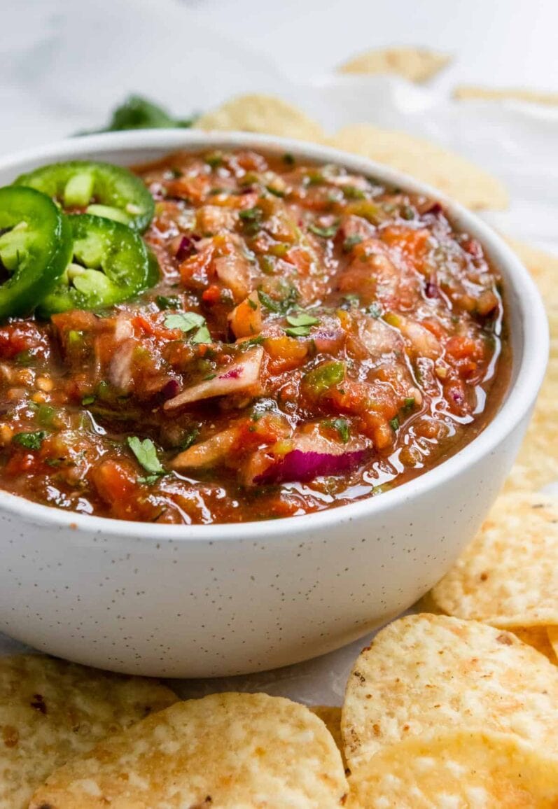 roasted tomato salsa in a white speckled bowl surrounded by chips