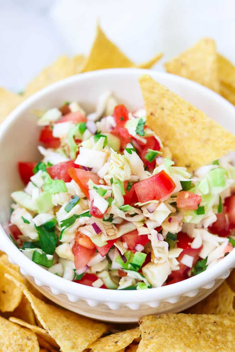 Mexican cabbage salsa in a white bowl surrounded by chips