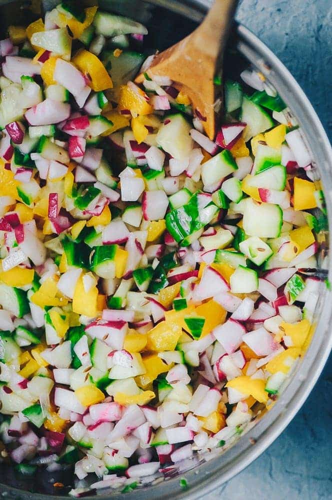 radish and cucumber salad in a white bowl on a blue table