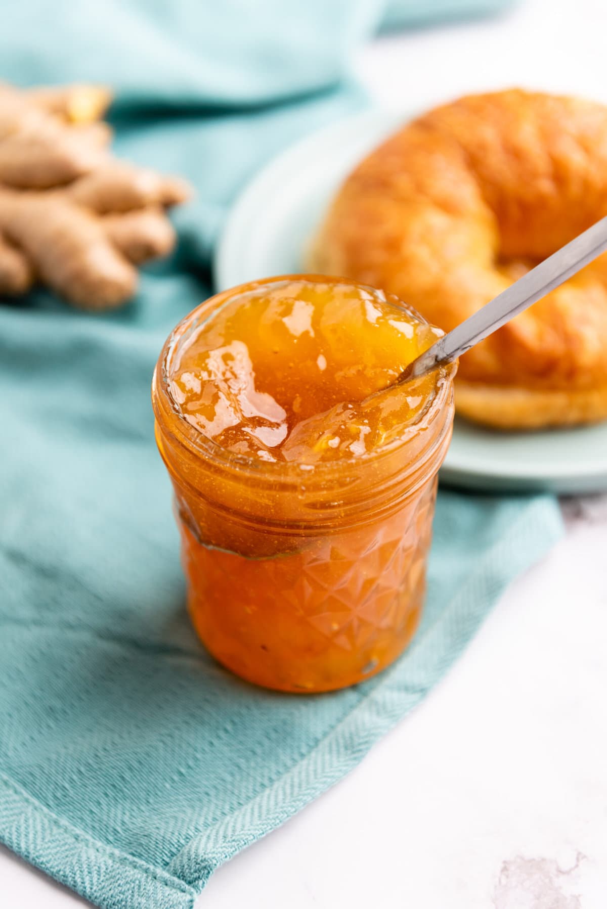 close up of jar of jam on a white table with a spoon in it