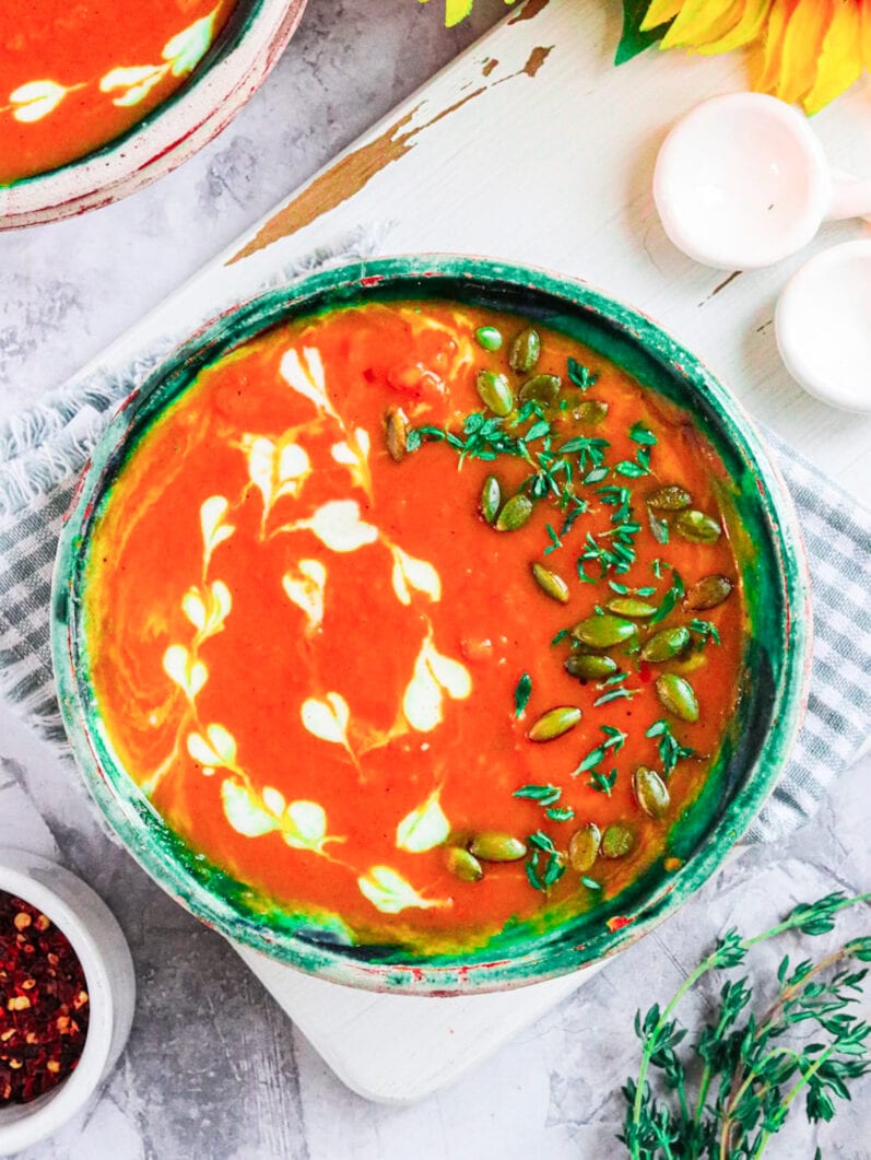 orange soup in a green bowl on a white table