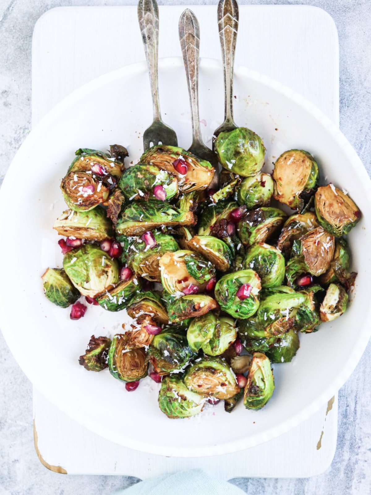 air fryer brussel sprouts topped with pomegranate and coconut on a white plate