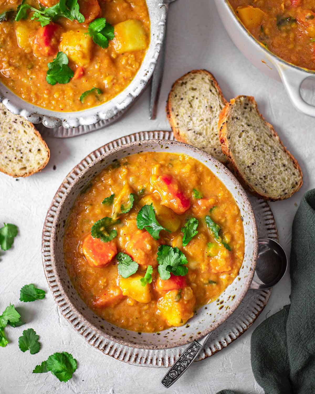 2 bowls of Thai red curry lentil soup on a white table