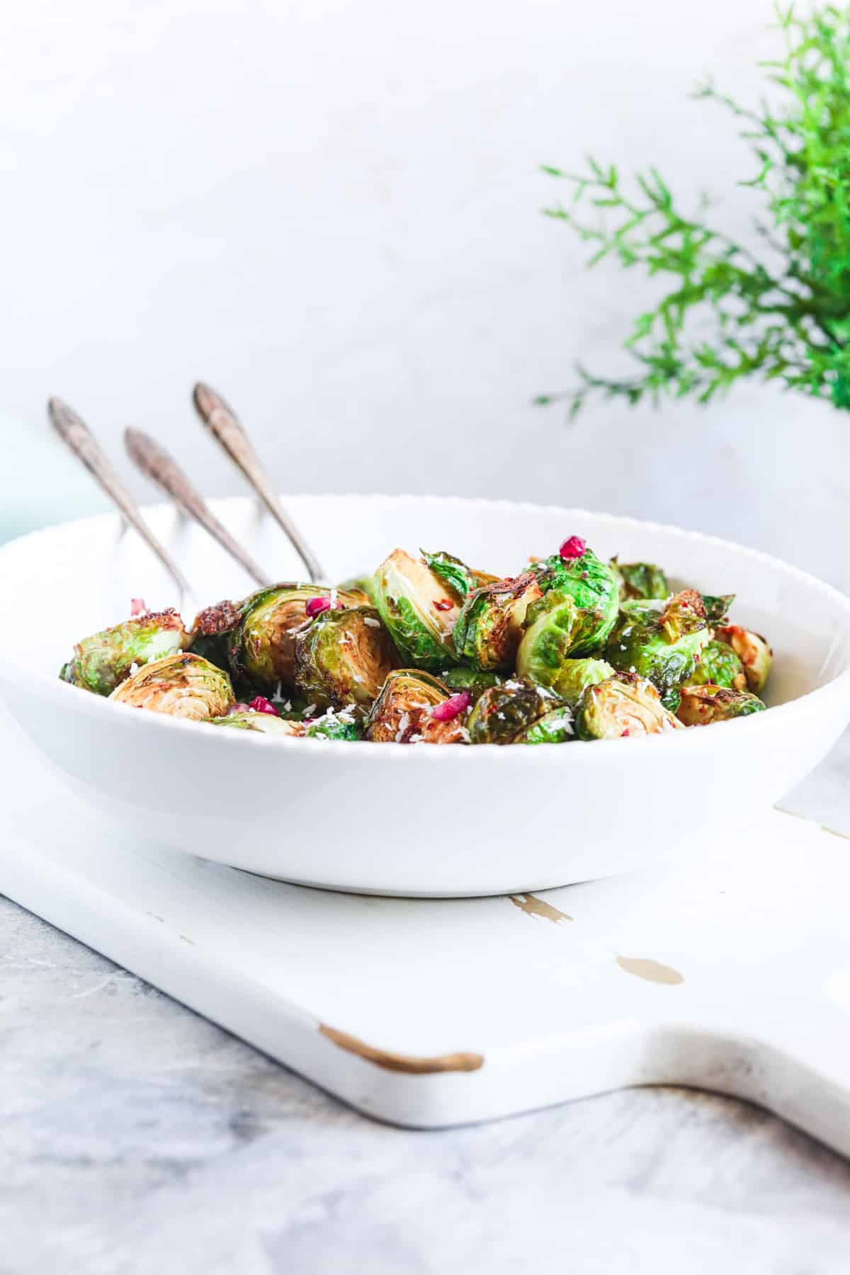 side view of a white bowl full of air fryer brussel sprouts