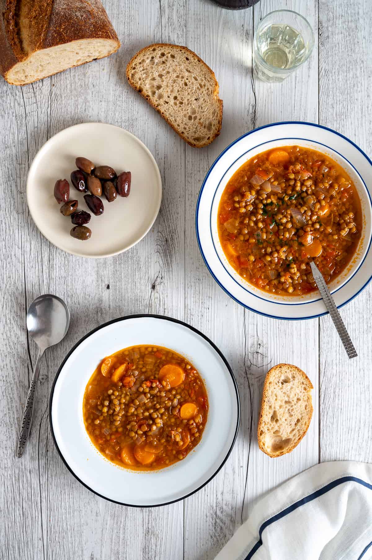 2 bowls of Greek lentil soup on distressed white wood