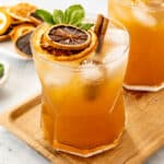 two orange drinks on a wood serving dish