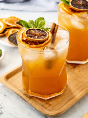 two orange drinks on a wood serving dish
