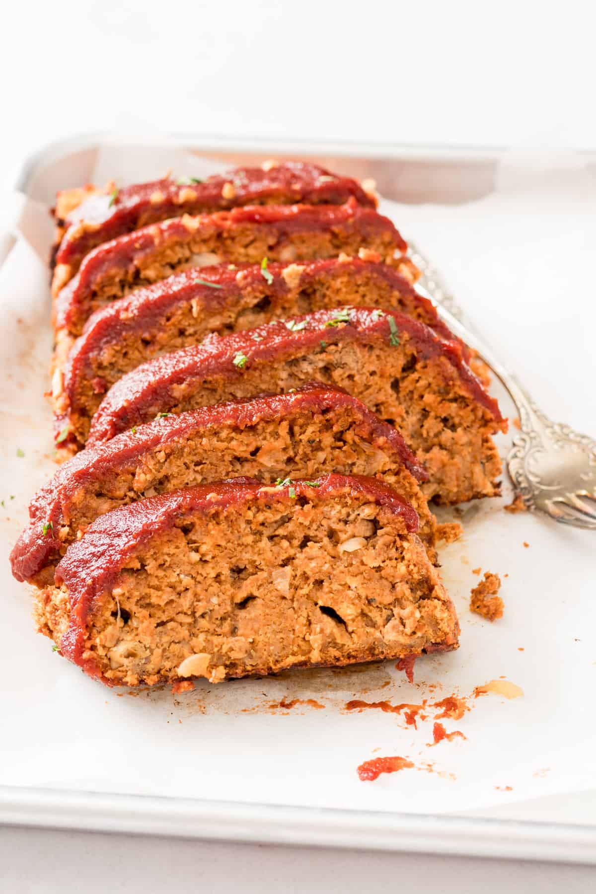 slices of beyond meat meatloaf topped with ketchup on a white cutting board