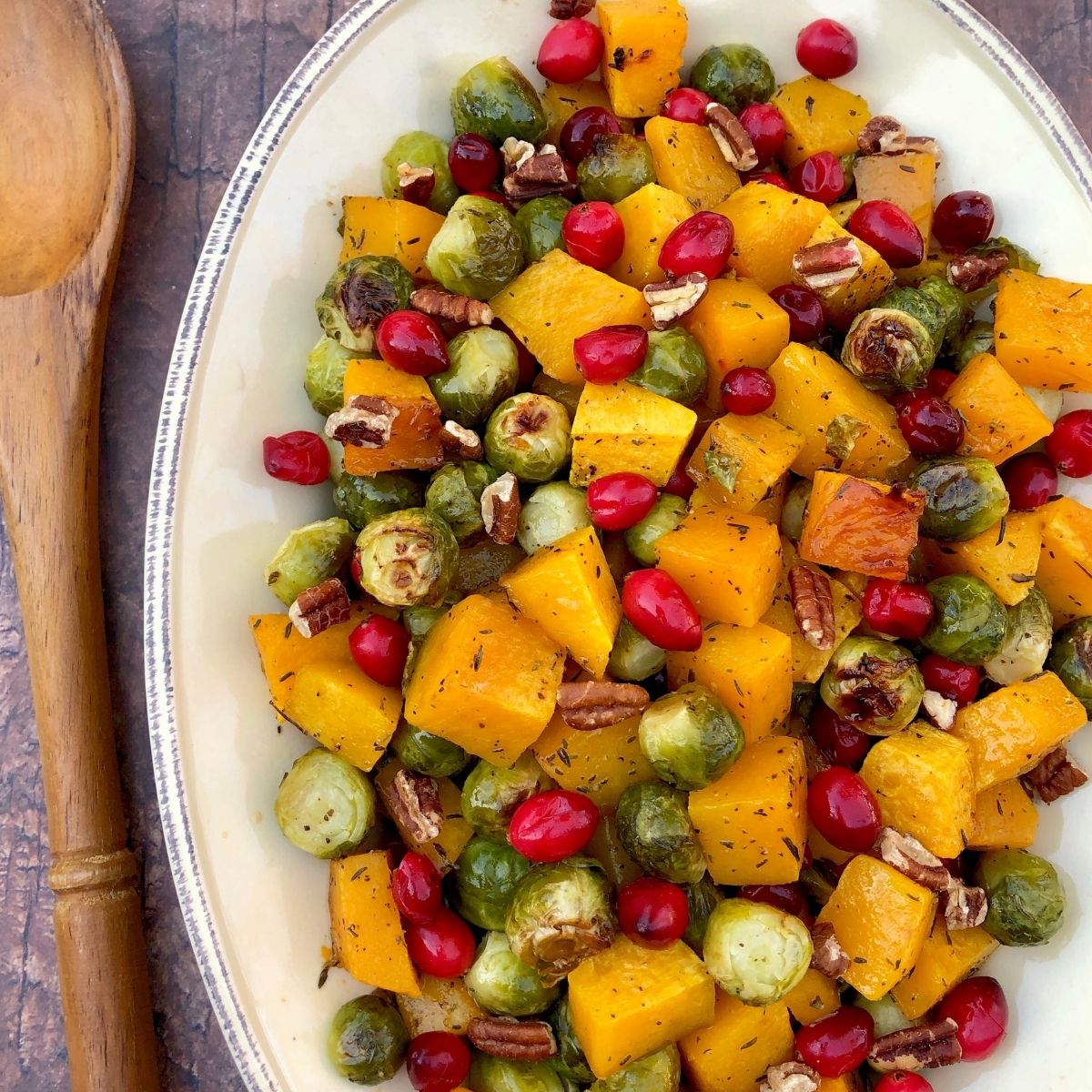 roasted butternut squash, brussel sprouts and cranberries on a white platter