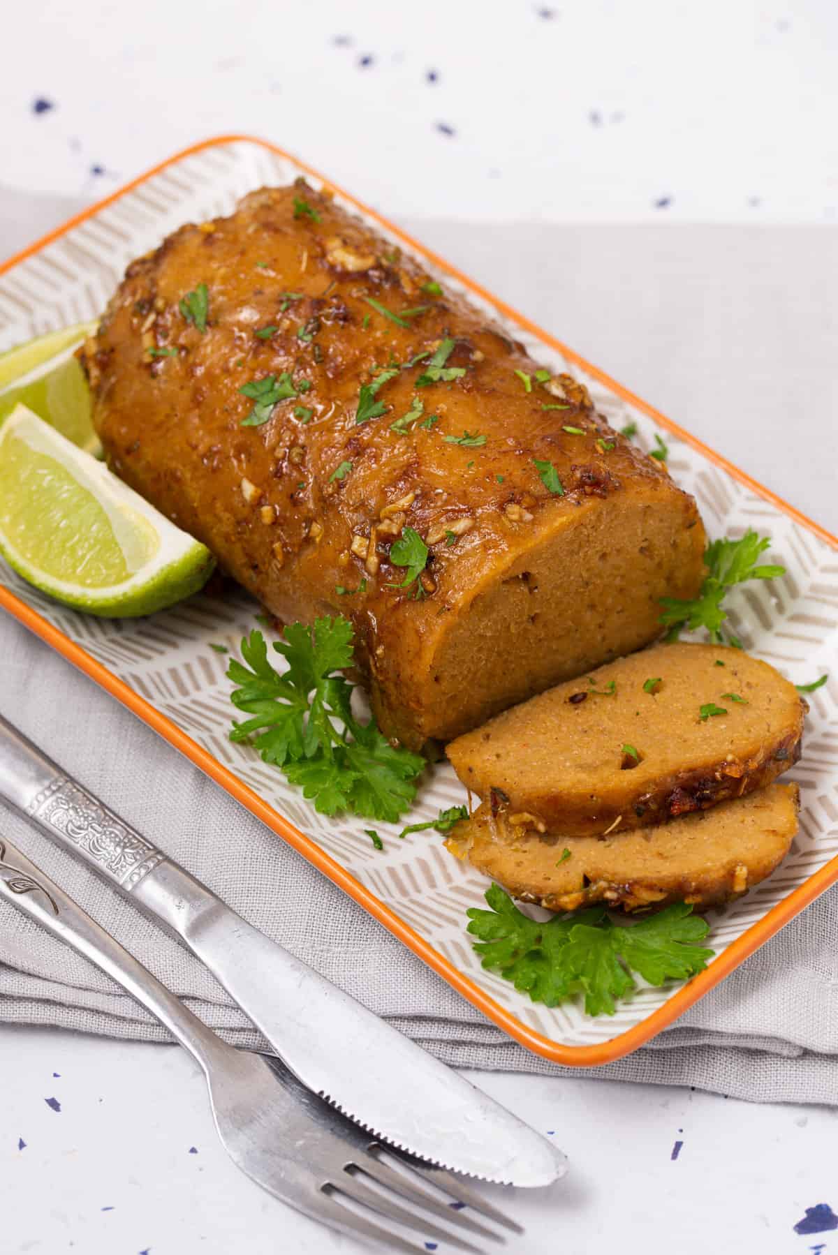 slices of vegan turkey roast on a white serving platter