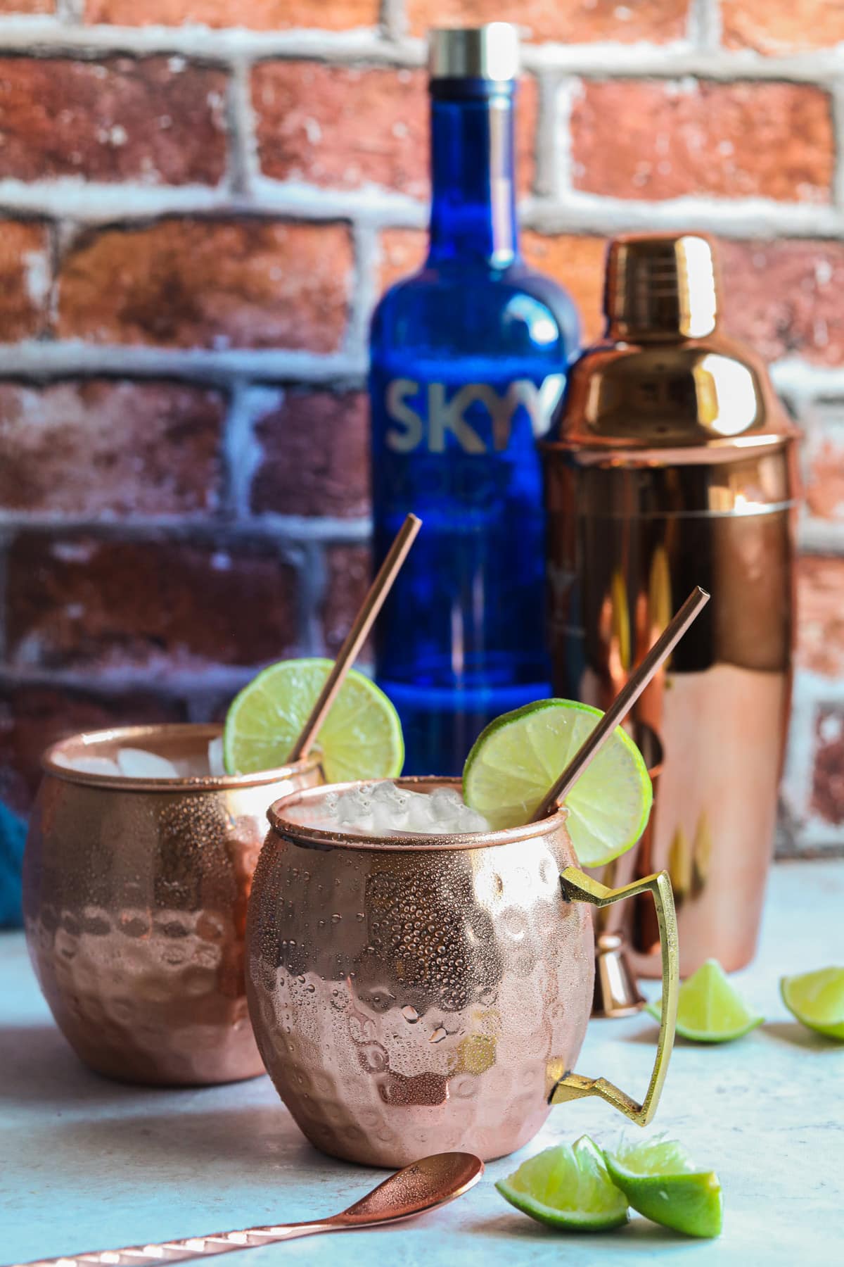 2 Moscow mules in copper mugs garnished with limes