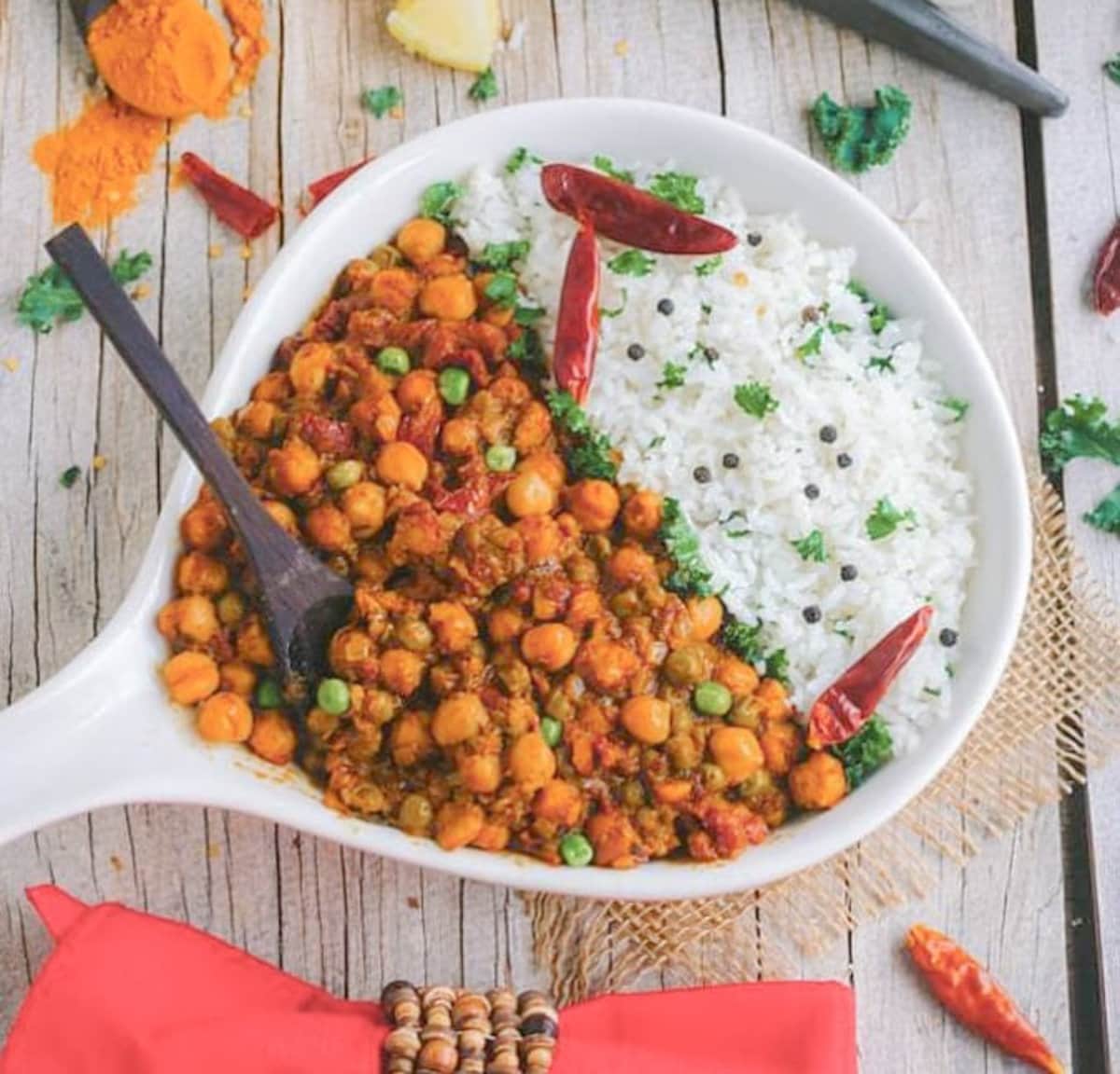 chickpea coconut curry in a white bowl with a side of rice