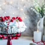 raspberry vegan pavlova on a red cake plate