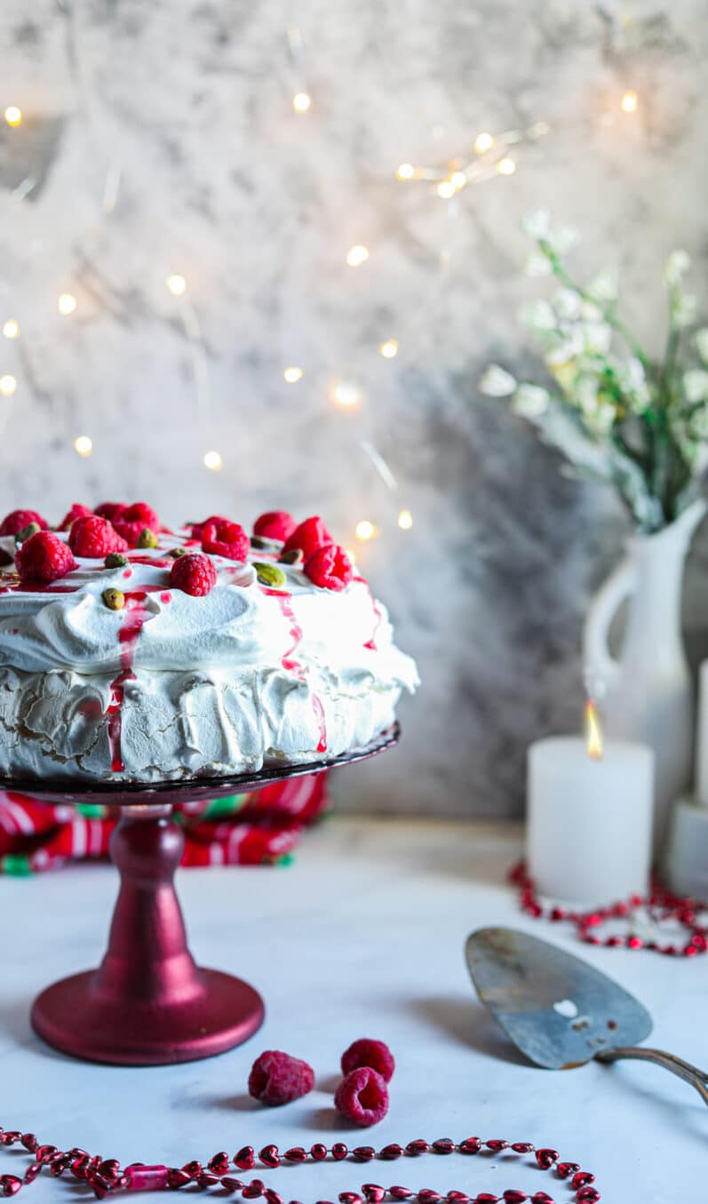 raspberry vegan pavlova on a red cake plate