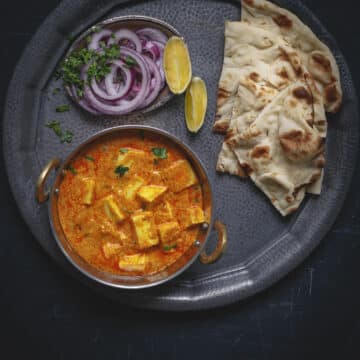 a bowl of vegan paneer butter masala on a black cooking tray