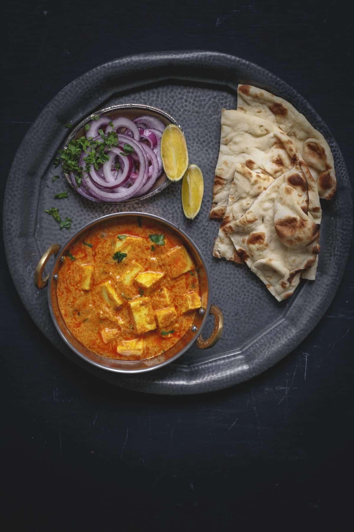 a bowl of vegan paneer butter masala on a black cooking tray