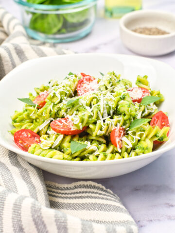 avocado pasta topped with tomatoes in a white bowl