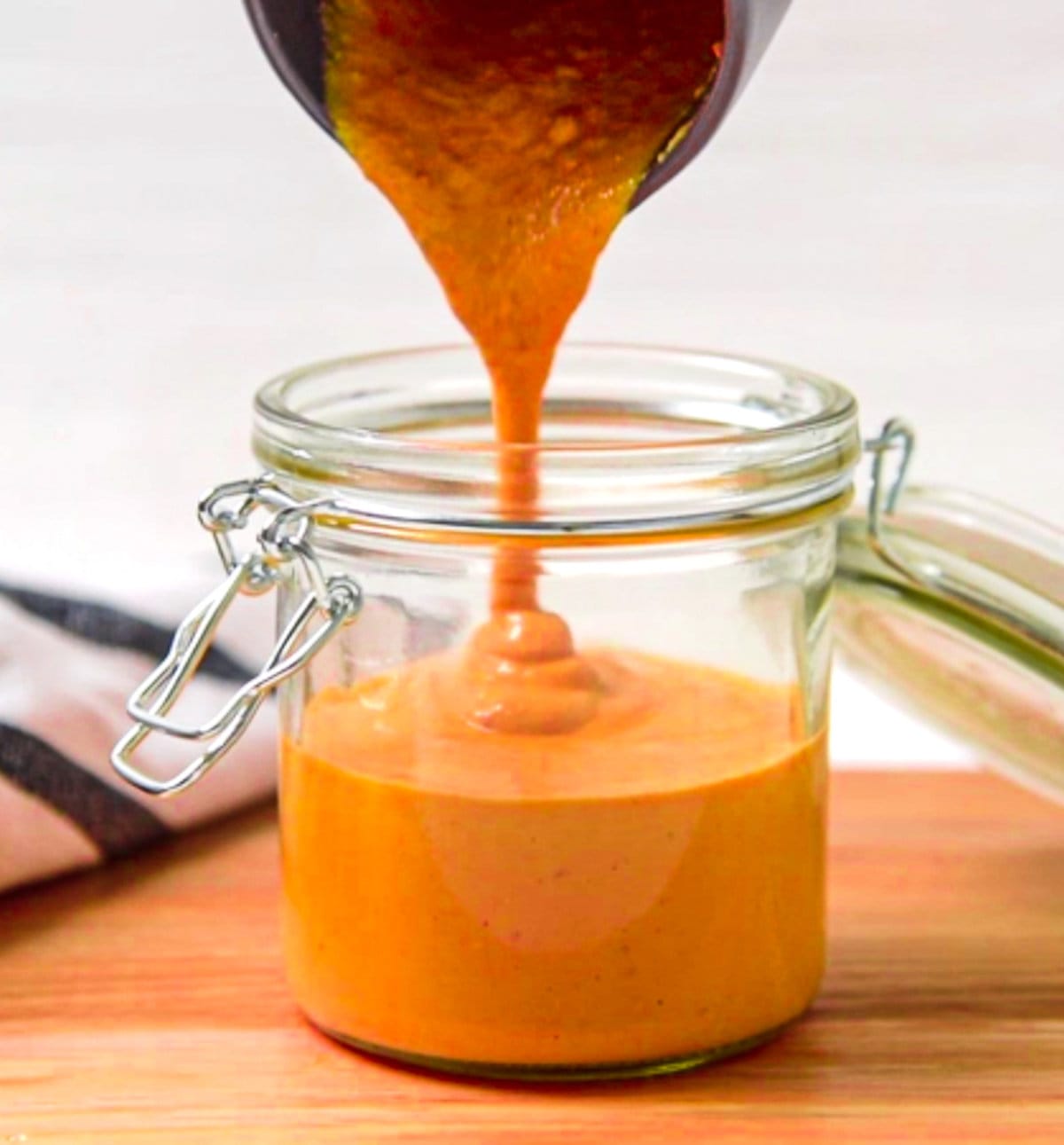 sauce being poured into a glass jar