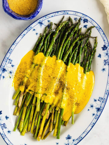 overhead view of a plate of green asparagus with a yellow sauce