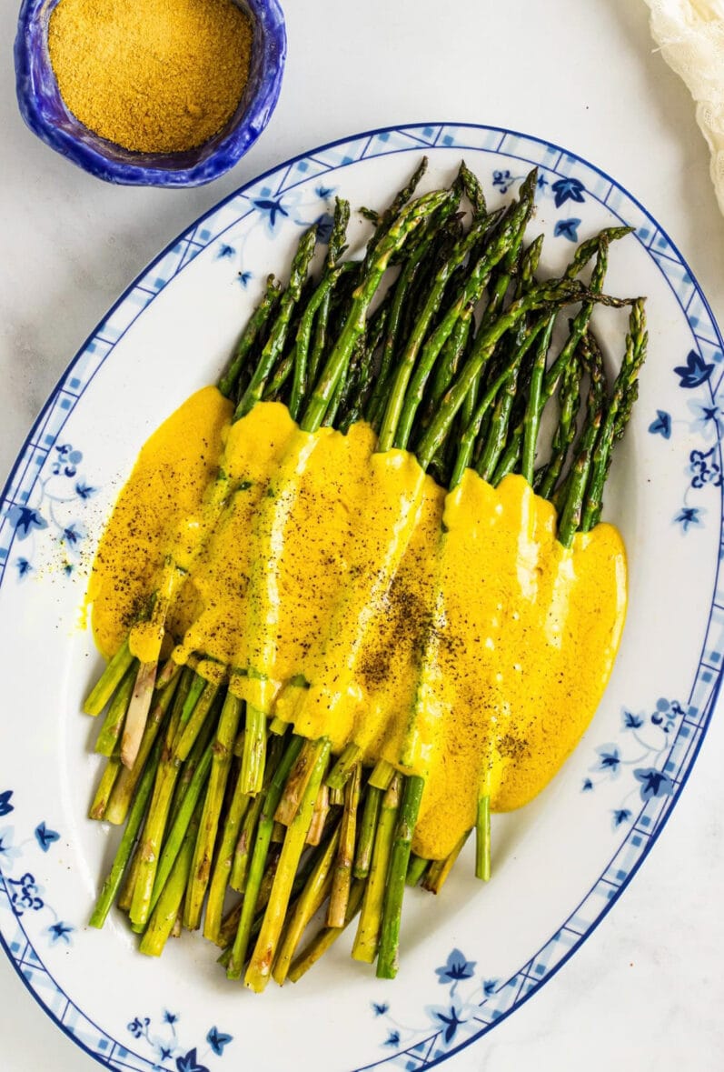 overhead view of a plate of green asparagus with a yellow sauce