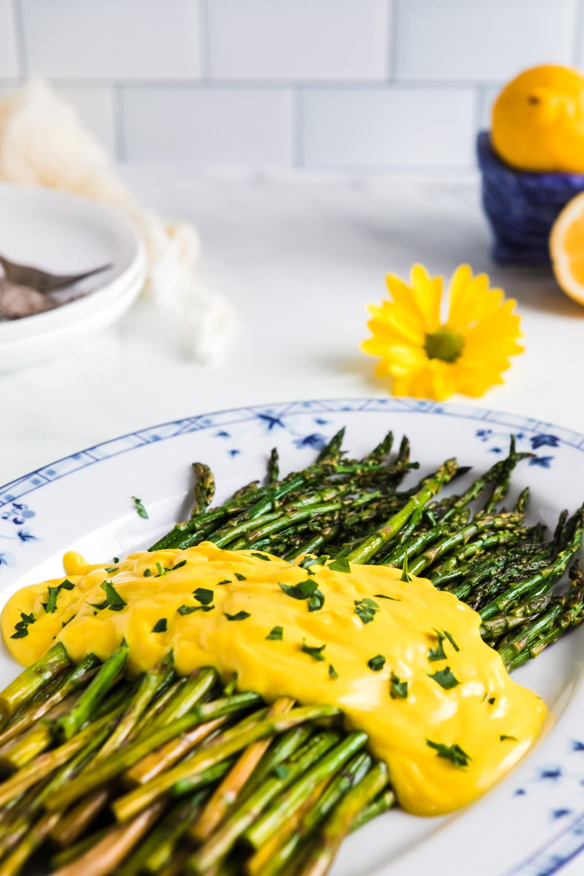 plate of asparagus on a white table with hollandaise sauce and parsley