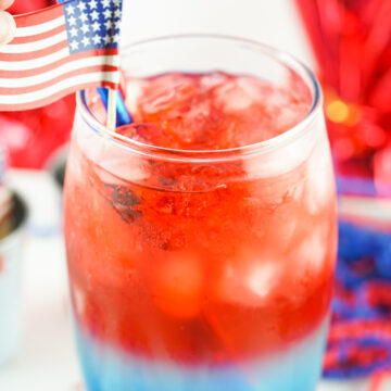 red white and blue cocktail with flag in it on white table