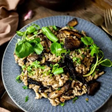 plate of mushroom risotto on a wood table